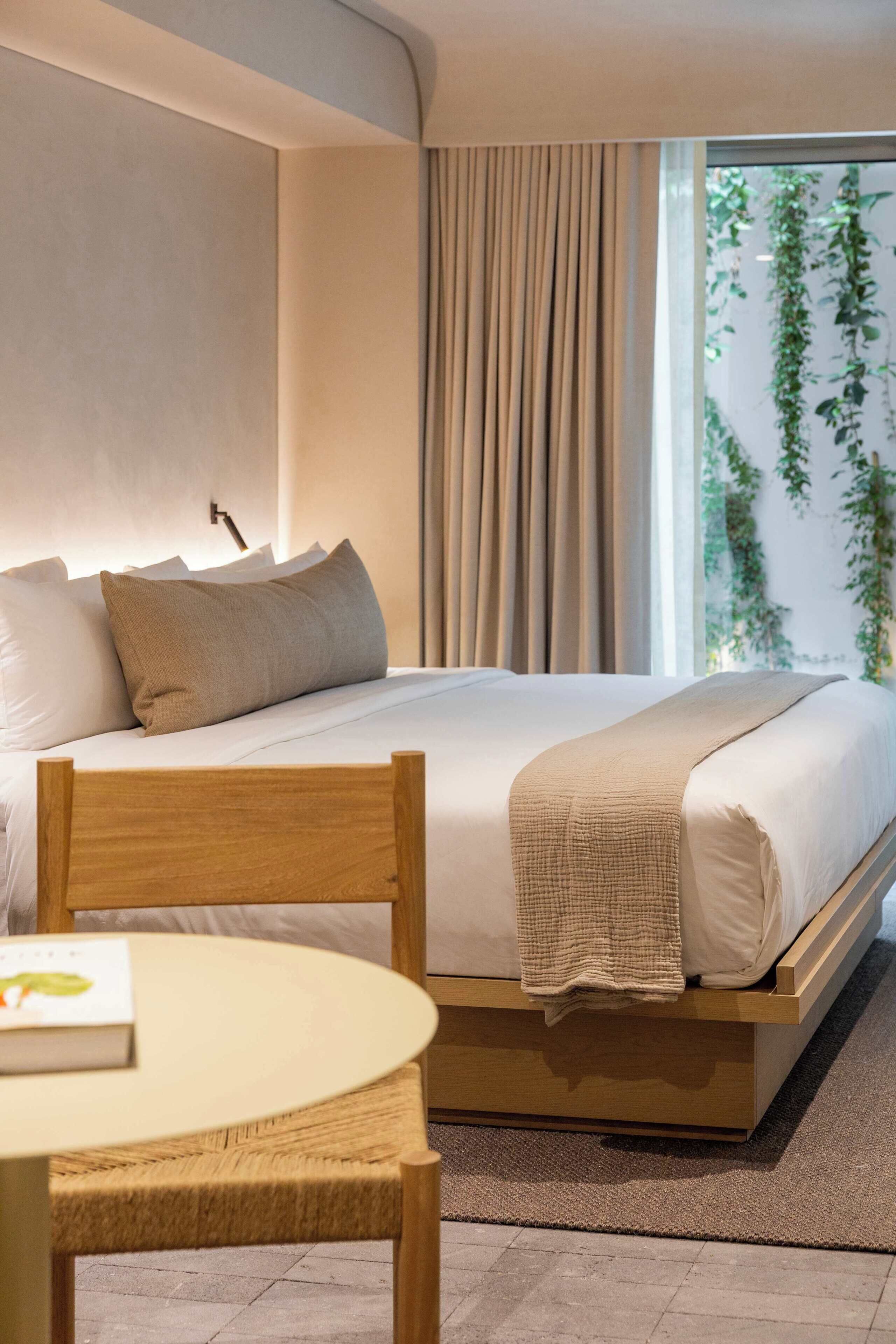 A modern bedroom with a bed, a bedside table, and a window with curtains.