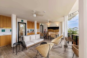 A modern interior with a sofa, chairs, a dining table, and a balcony with plants.