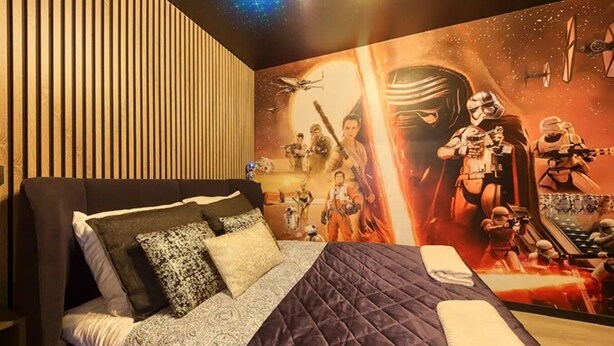 A bedroom with a Star Wars-themed mural, a bed with patterned bedding, and a wooden slat wall. - Starwars Disney 10 minutes by car. Cuisine équipée et Wi-Fi performant (Bussy-Saint-Georges)