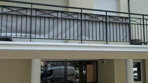 A building entrance with a gated driveway, a balcony with a railing, and a vehicle inside. - Starwars Disney 10 minutes by car. Cuisine équipée et Wi-Fi performant (Bussy-Saint-Georges)