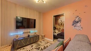 A modern living room with a flat-screen TV, a console table, a patterned rug, and a sofa. - Starwars Disney 10 minutes by car. Cuisine équipée et Wi-Fi performant (Bussy-Saint-Georges)
