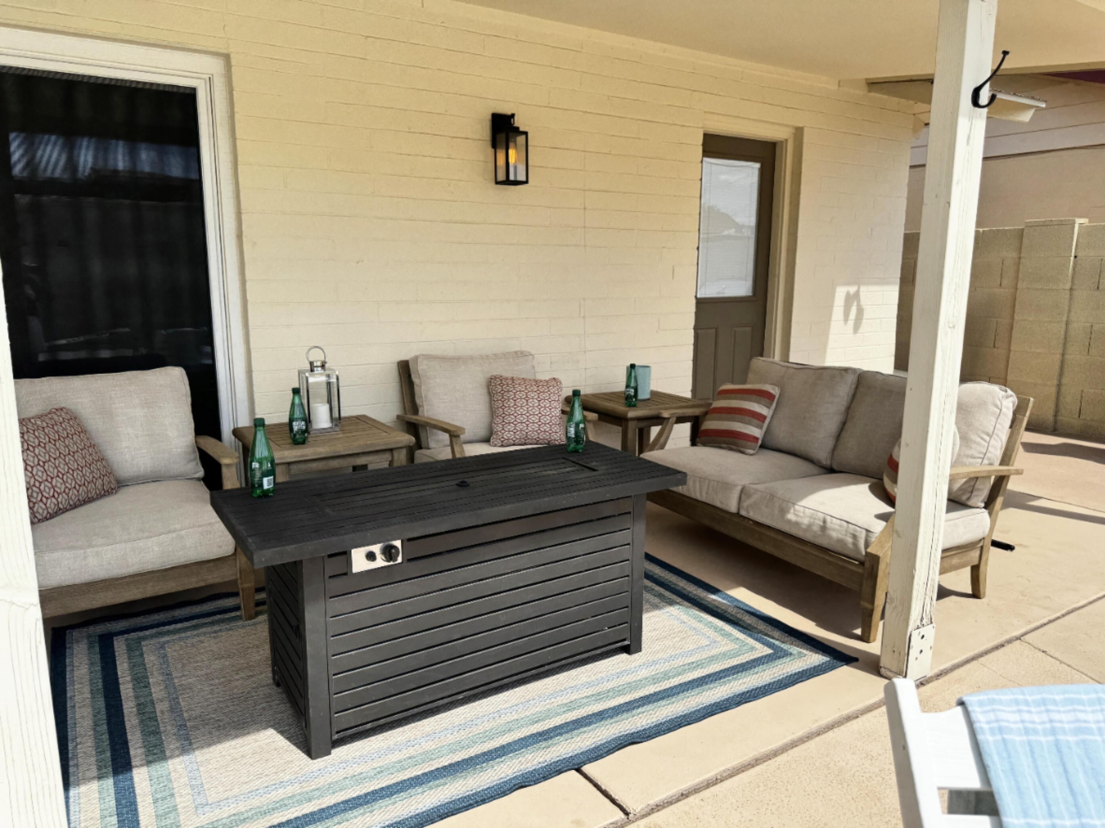 A covered patio area with a black coffee table, two sofas, and a small table with drinks.