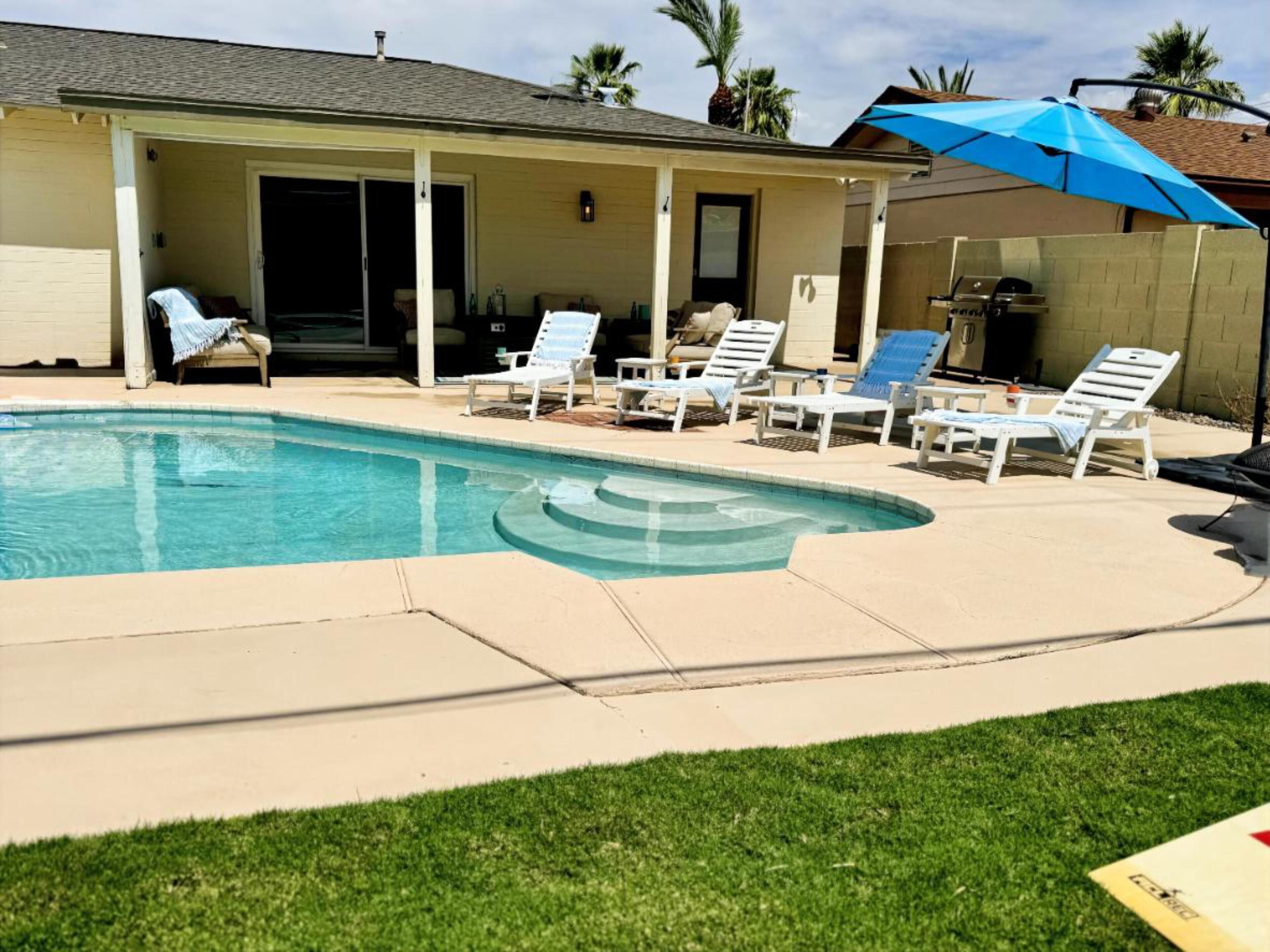 Un jardin avec une piscine, des chaises longues et un patio couvert.
