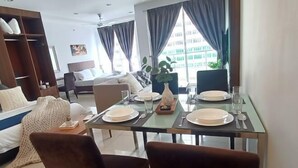 Un coin repas avec une table dressée pour deux personnes, un canapé, un lit et une armoire.
