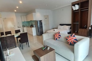A modern living room with a sofa, a coffee table, and a dining area with chairs and a table. - Mansion One by LS Staycation (George Town)