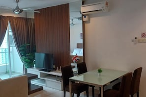 A modern living room with a flat-screen TV, a dining table, and a sofa. - Mansion One by LS Staycation (George Town)