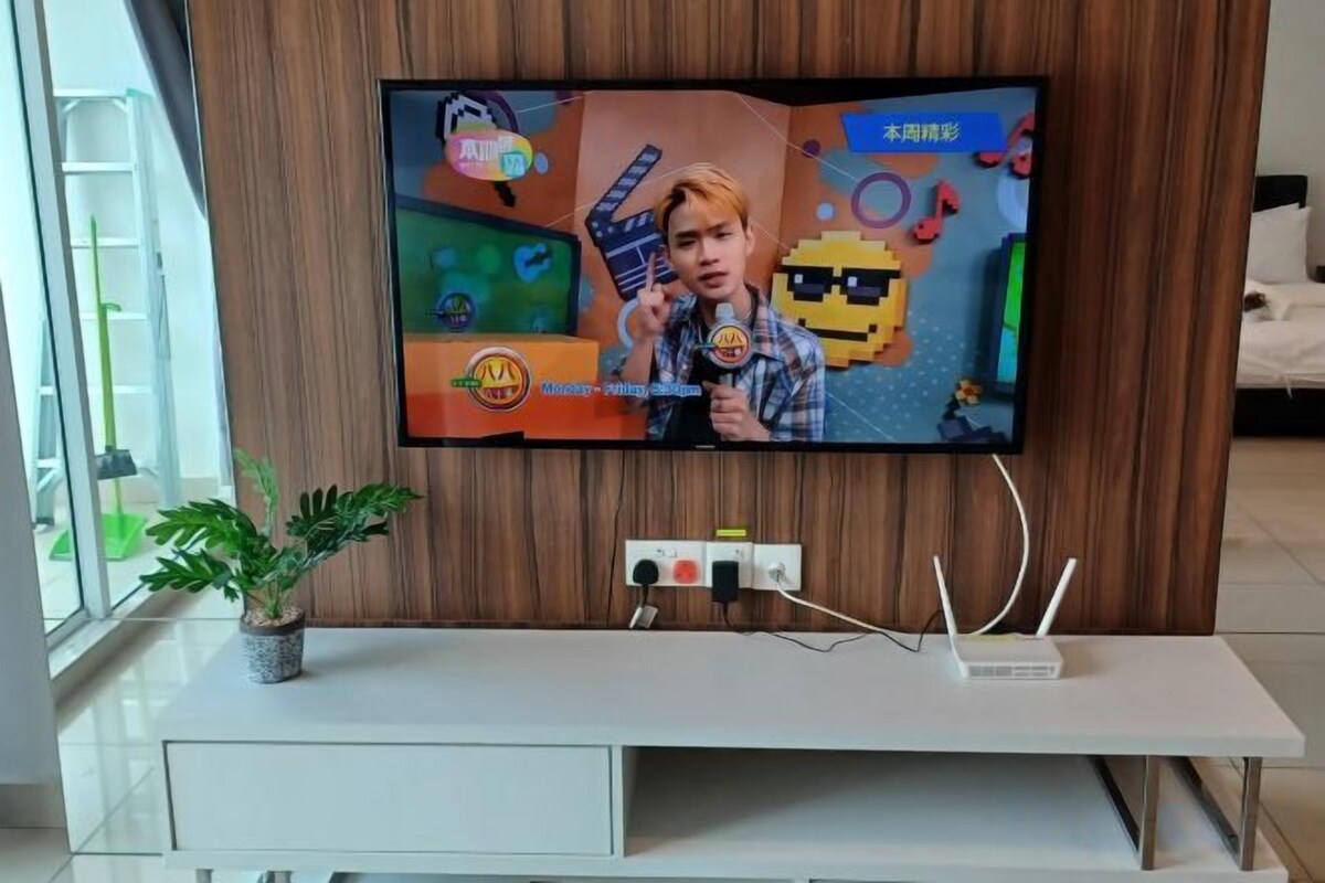 A flat-screen TV mounted on a wall with a wooden panel backdrop.