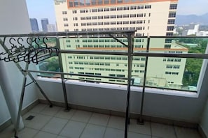 A balcony with a metal rack and a view of a building with multiple windows. - Mansion One by LS Staycation (George Town)