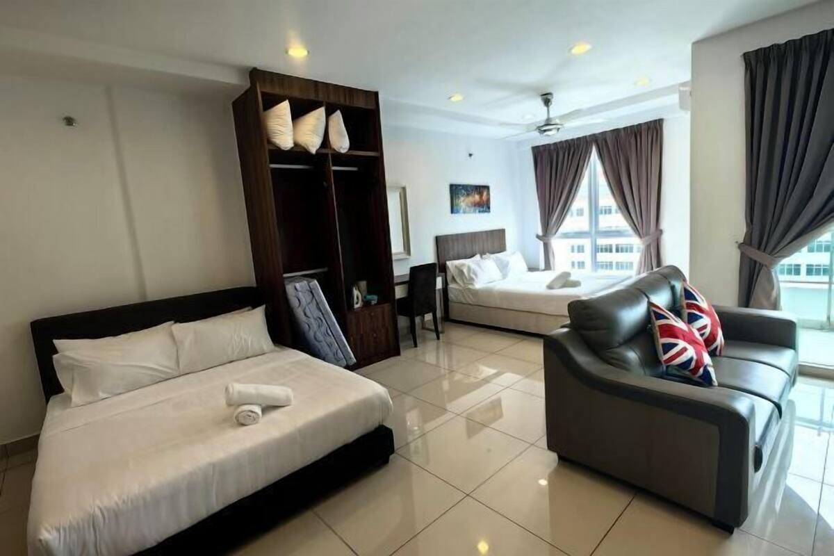 A hotel room with a bed, a sofa, a wardrobe, and a desk.