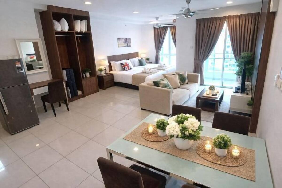 A modern hotel room with a bed, sofa, dining table, and a wardrobe.