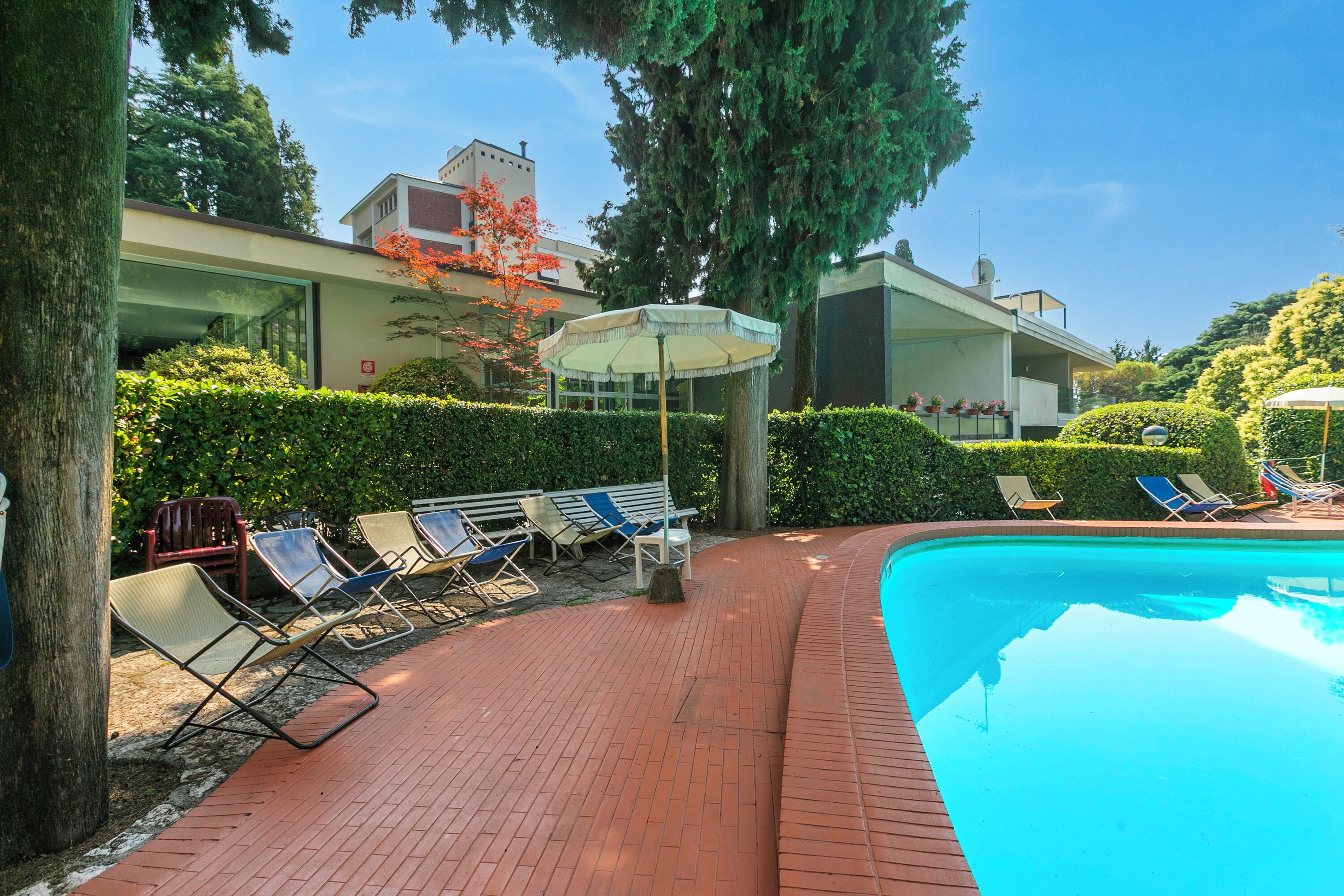 Un área de piscina con sillones de descanso y una pérgola.