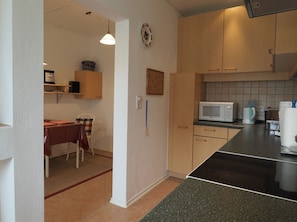 A compact kitchen with a microwave, toaster, and coffee maker. There is a dining area with a table and chairs. - Apartment 'Koppelblick' with Private Terrace, Shared Garden and Wi-Fi (Plattenburg)
