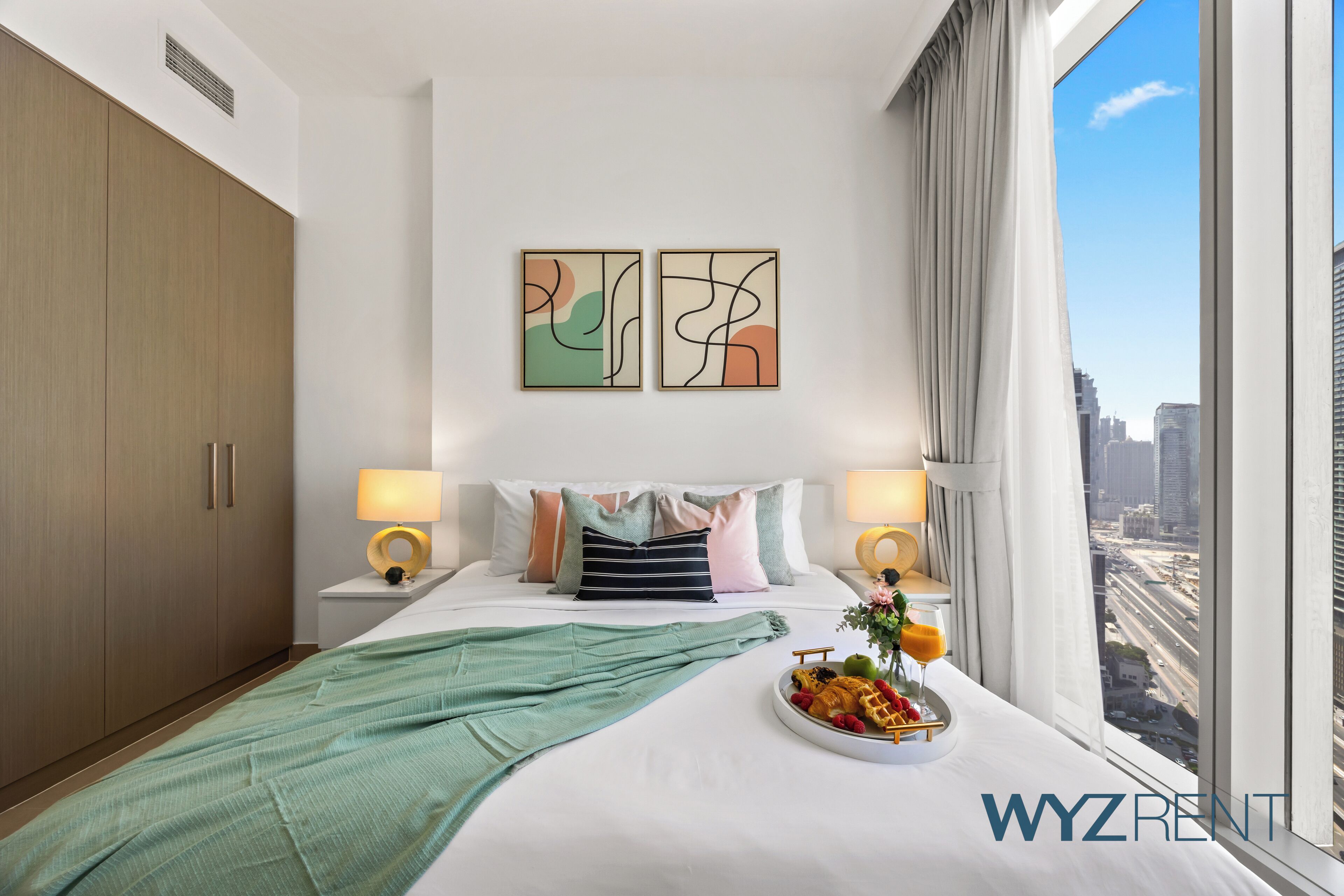 Ein modernes Hotelzimmer mit einem großen Bett, zwei Nachttischen, Blick auf die Stadt und abstrakter Wandkunst.