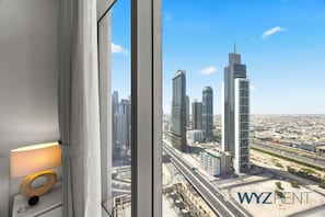Vista desde una ventana sobre un paisaje urbano con edificios altos, una lámpara en el alféizar y el texto 'WYZRENT' en la esquina inferior derecha.