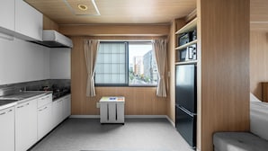 A modern kitchen with white cabinets, a black refrigerator, a microwave, and a small cart. - MITTO (Sapporo)