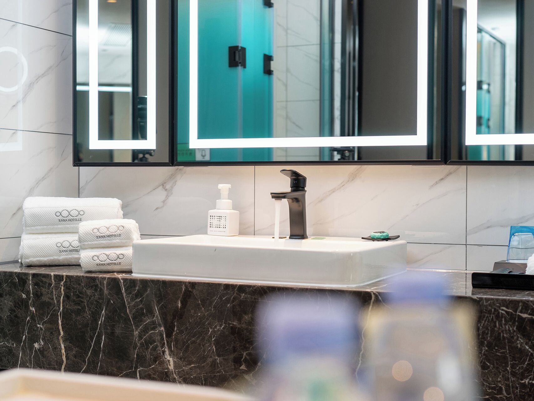 Un bany amb un lavabo de marbre, un mirall i tovalloles perfectament arremegades.
