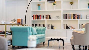 A modern living room with a teal sofa, a white coffee table, and a bookshelf filled with books.