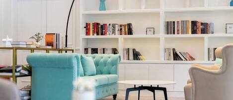 Un salon moderne avec un canapé de couleur turquoise, une table basse blanche et une bibliothèque remplie de livres.