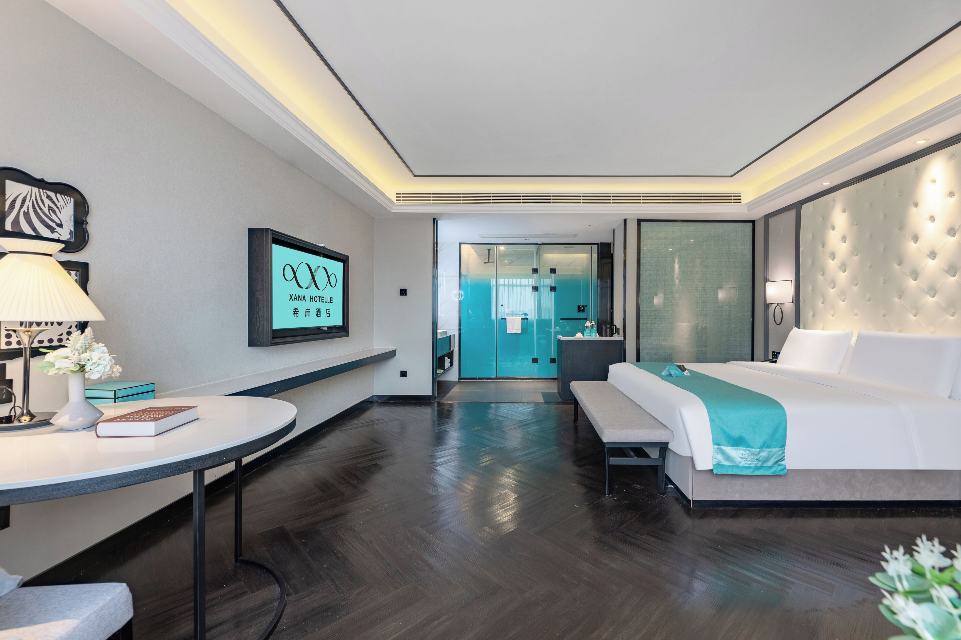 A hotel room with a bed, bedside table, lamp, and a wall-mounted TV.