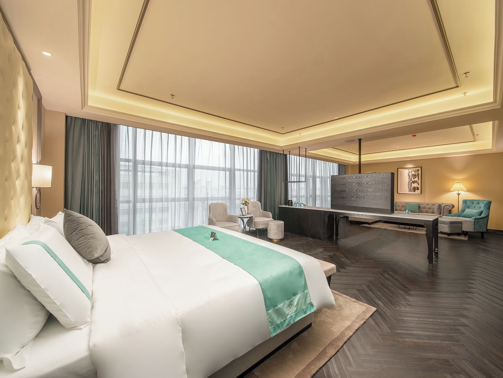 A hotel room with a large bed, a desk, a sofa, and a TV.