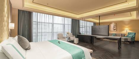 A hotel room with a large bed, a desk, a sofa, and a TV.