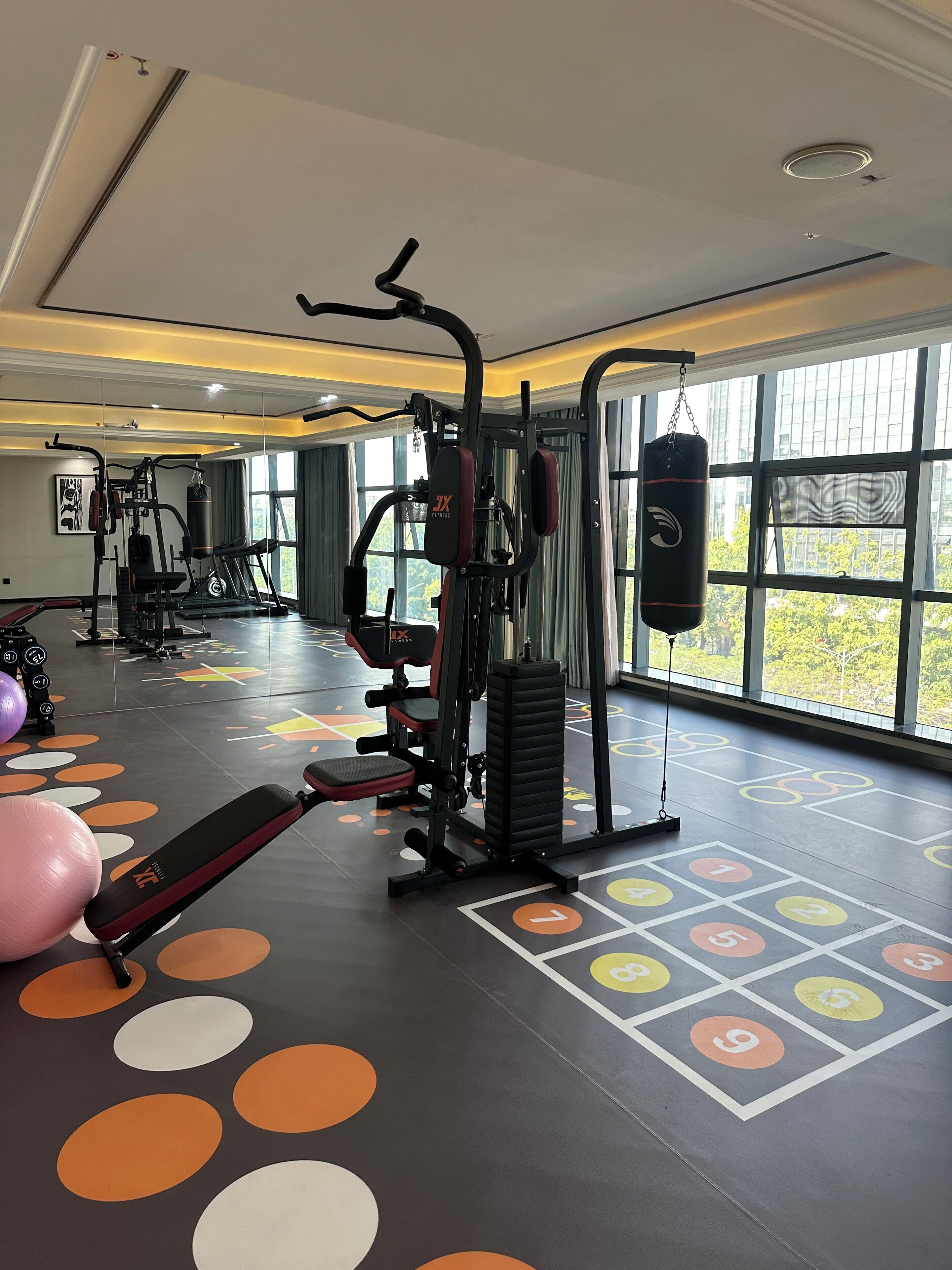 Un gimnasio con equipamiento de ejercicio, un saco de boxeo y un suelo con secciones numeradas.