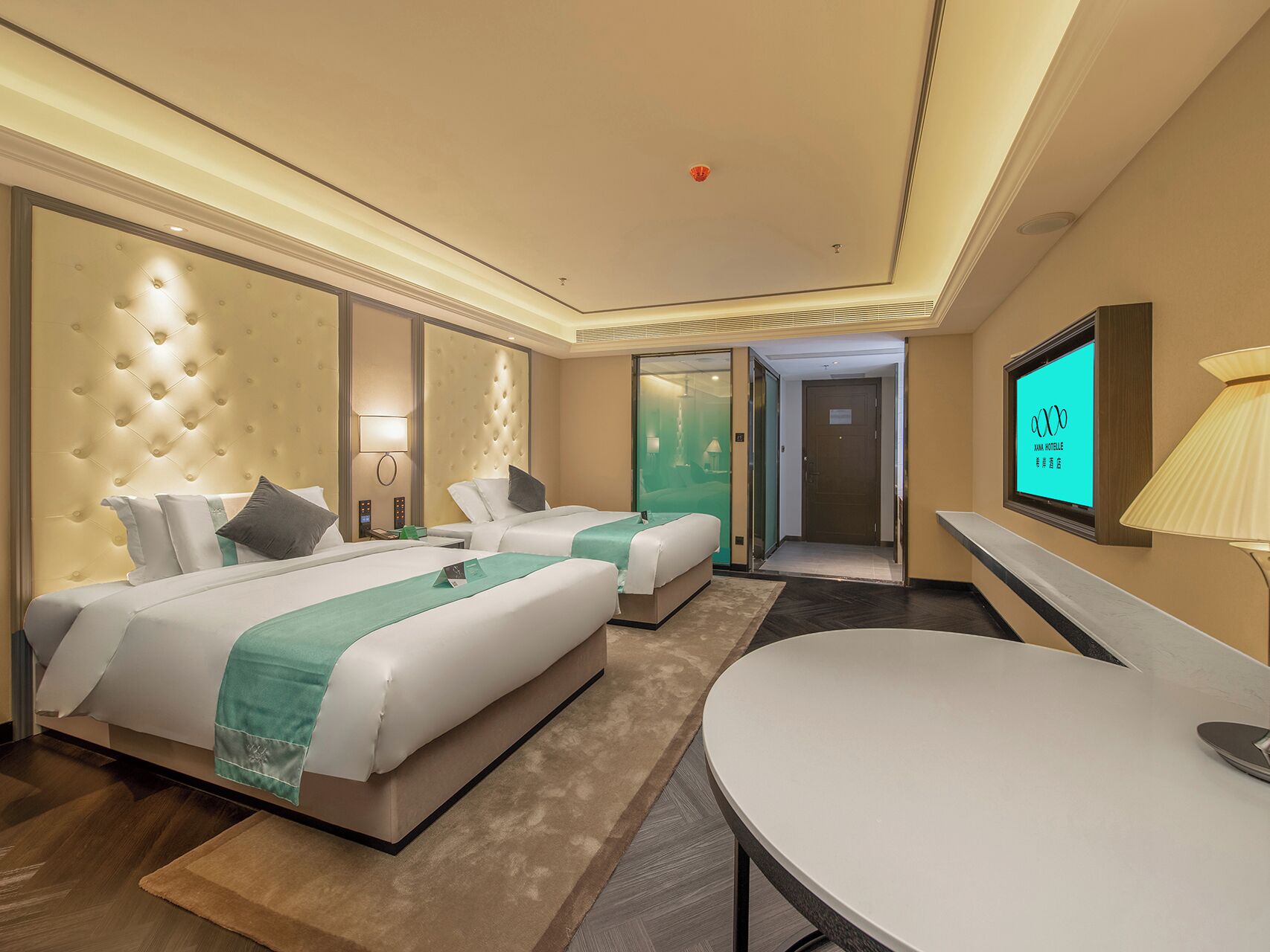 A hotel room with two beds, a TV, a desk, and a bathroom.
