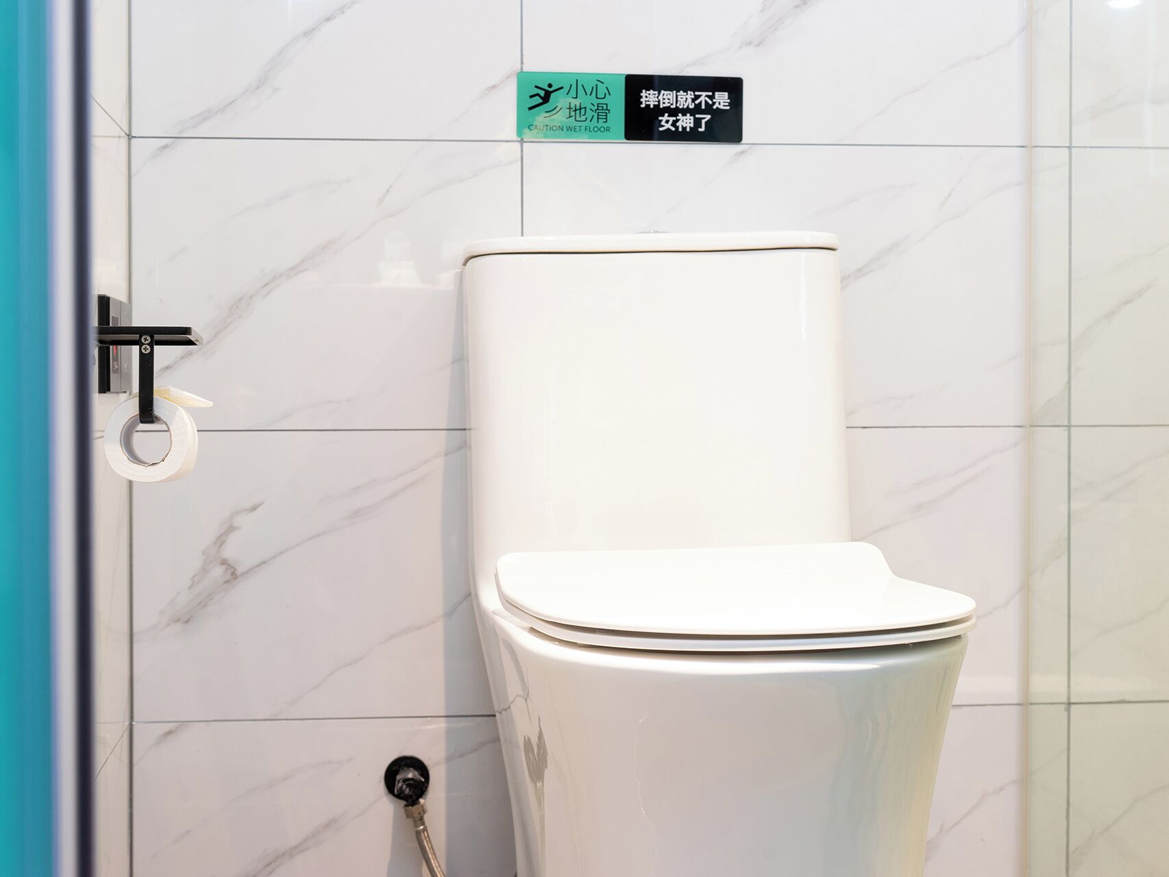 A toilet with a flush handle and a caution sign above it.