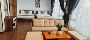 A hotel room with two single beds, a sofa, a wooden coffee table, a small side table, and a potted plant. - Romance Hotel (Da Lat)