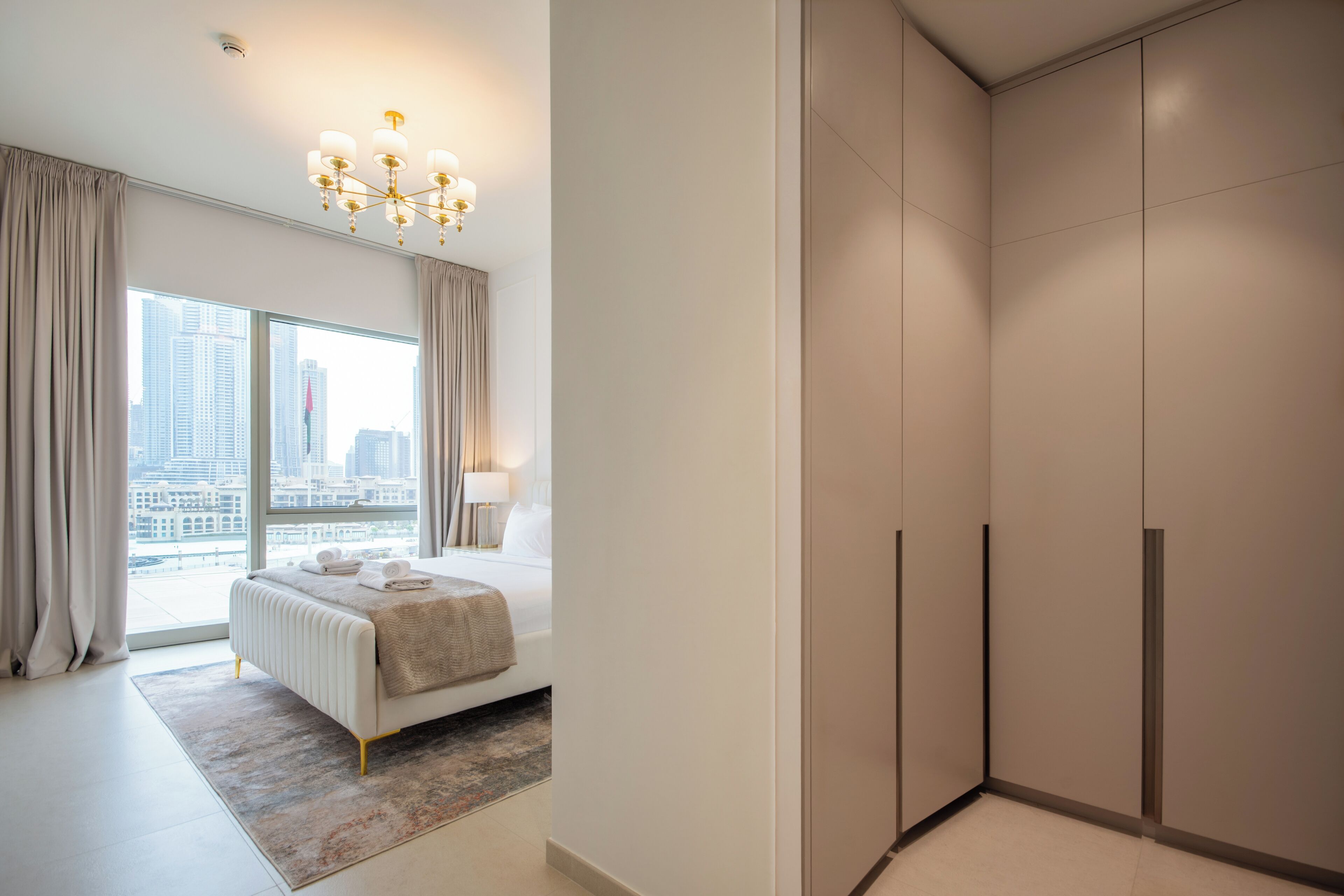 Un dormitorio moderno con una cama grande, vistas a la ciudad y un vestidor.