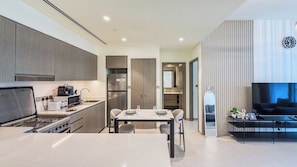 A modern kitchen with a dining area, a living room with a TV, and a large mirror. - Grande Signature Residences - Downtown (Dubai)