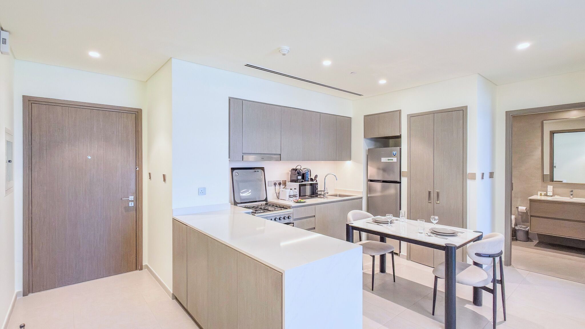 A modern kitchen with a central island, built-in appliances, and a dining area with chairs.