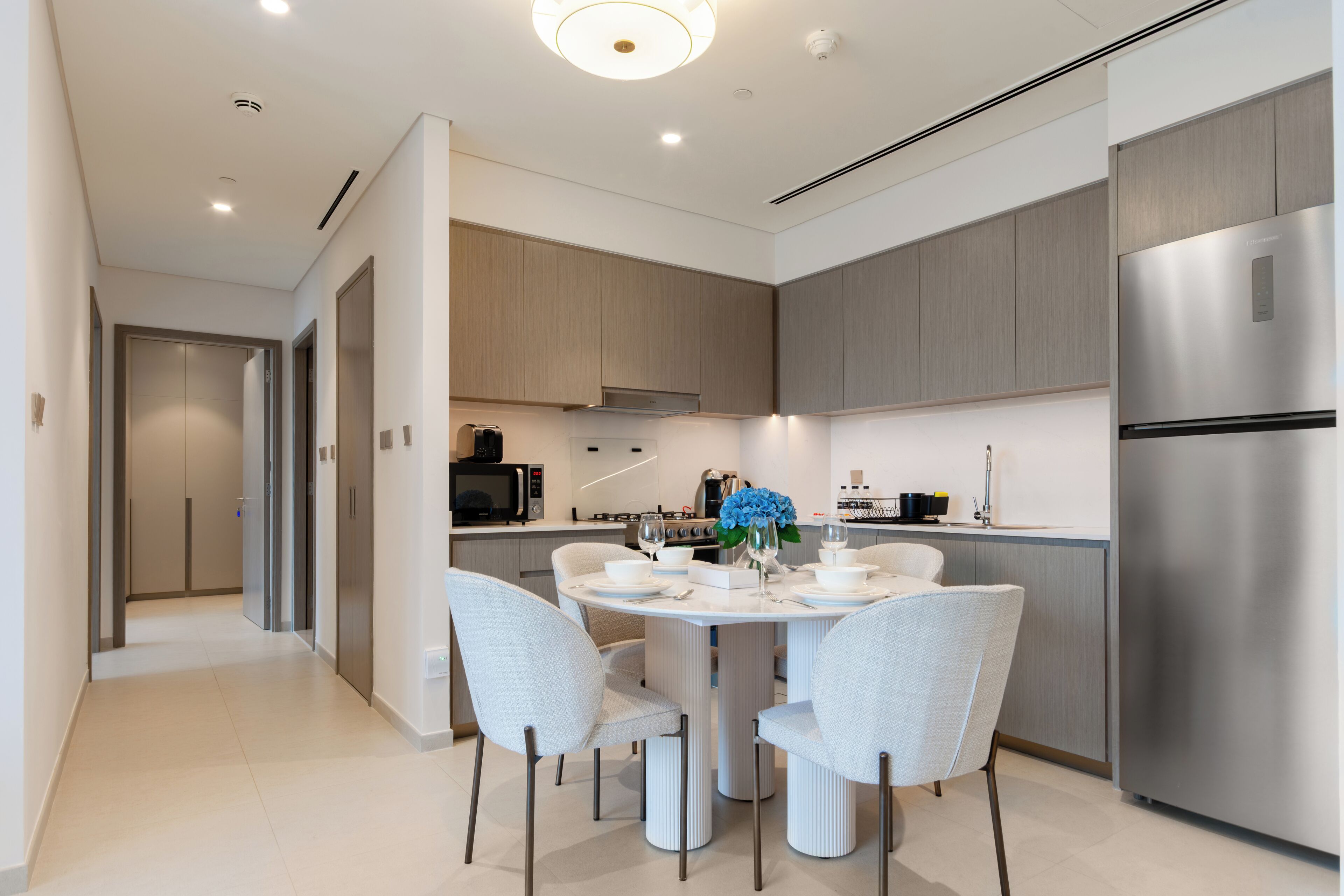 A modern kitchen with a central island, stainless steel appliances, and light-colored cabinetry.