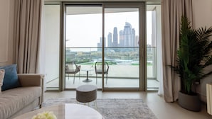 Uma sala de estar moderna com um sofá, uma mesa de centro e vista para o horizonte urbano através de amplas portas de vidro.