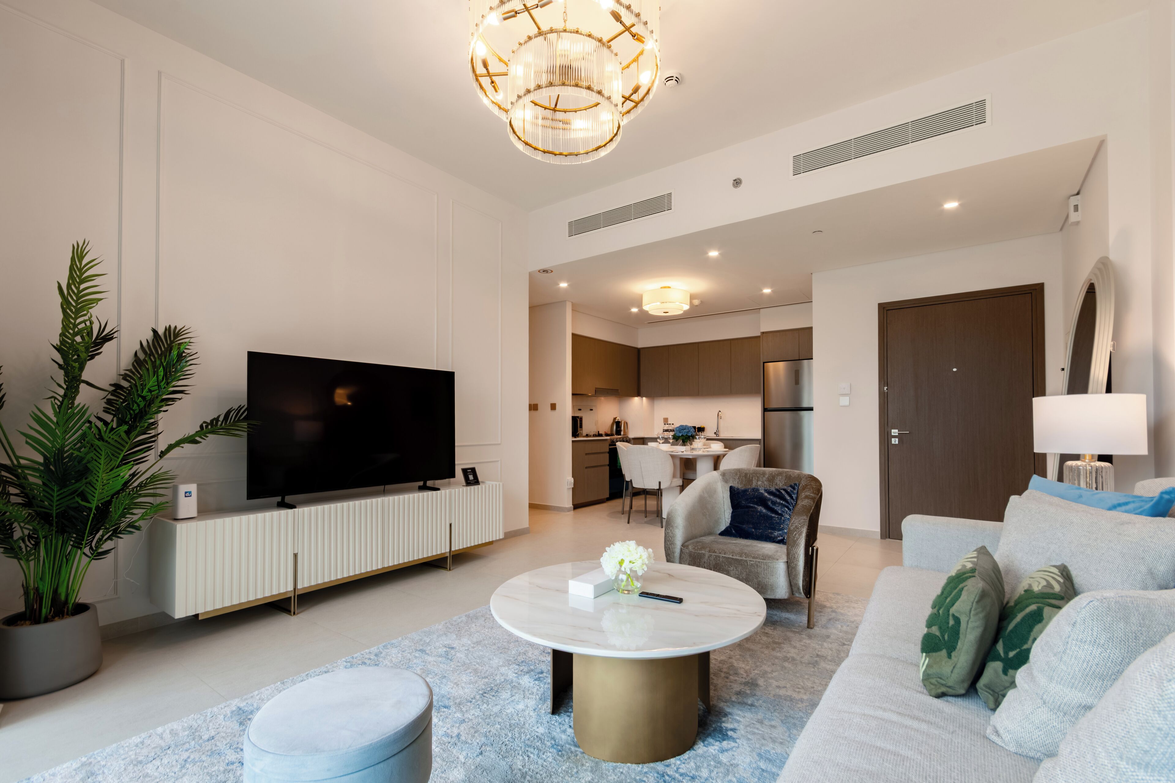 Uma sala de estar moderna com uma televisão de tela plana, uma mesa de centro redonda e um sofá.