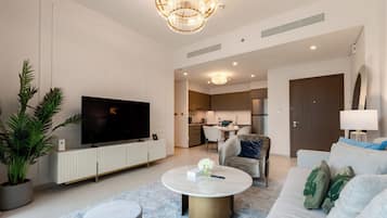 Uma sala de estar moderna com uma televisão de tela plana, uma mesa de centro redonda e um sofá.
