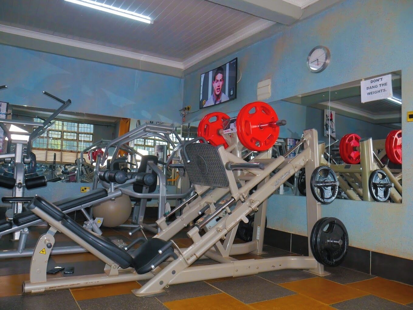 Un gimnasio con varios equipos de ejercicio, incluyendo máquinas de pesas y pesas libres.