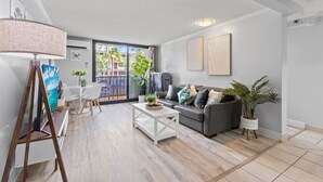 Un salon moderne avec un canapé gris, une table basse blanche et un tableau posé sur un chevalet.