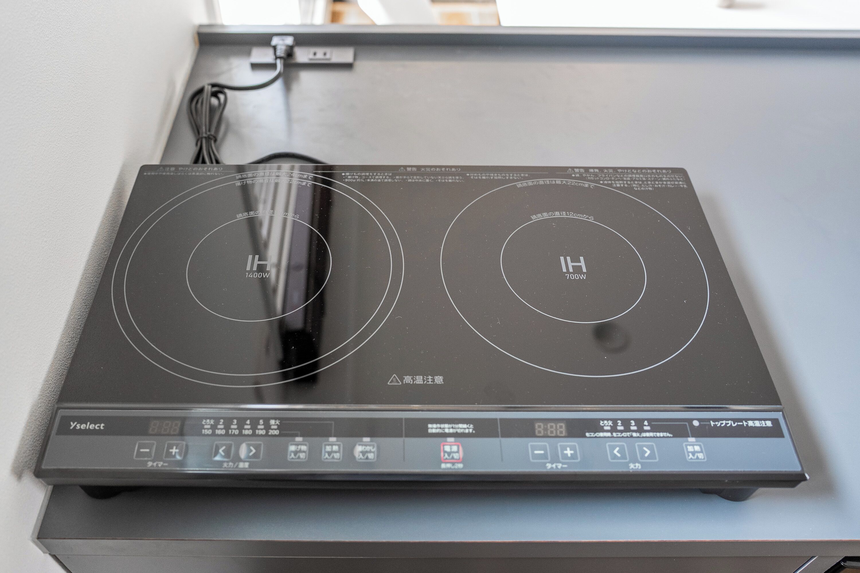 A black induction cooktop with a digital display and multiple control buttons.