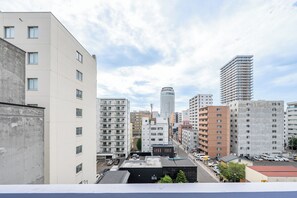 A cityscape with various multi-story buildings, including a prominent tall building with a cylindrical top. - MIMO (Sapporo)