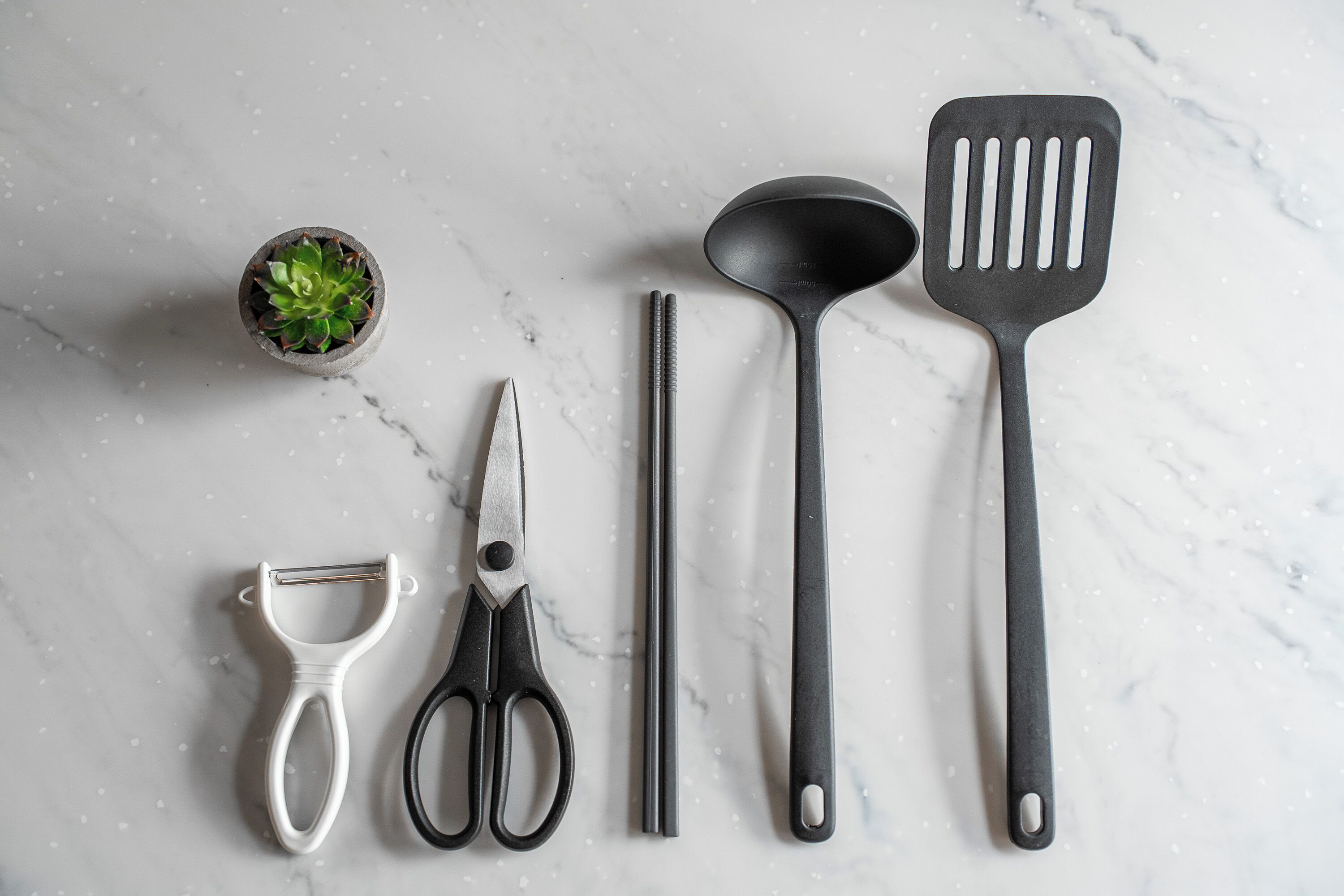 A kitchen utensil set on a marble surface.