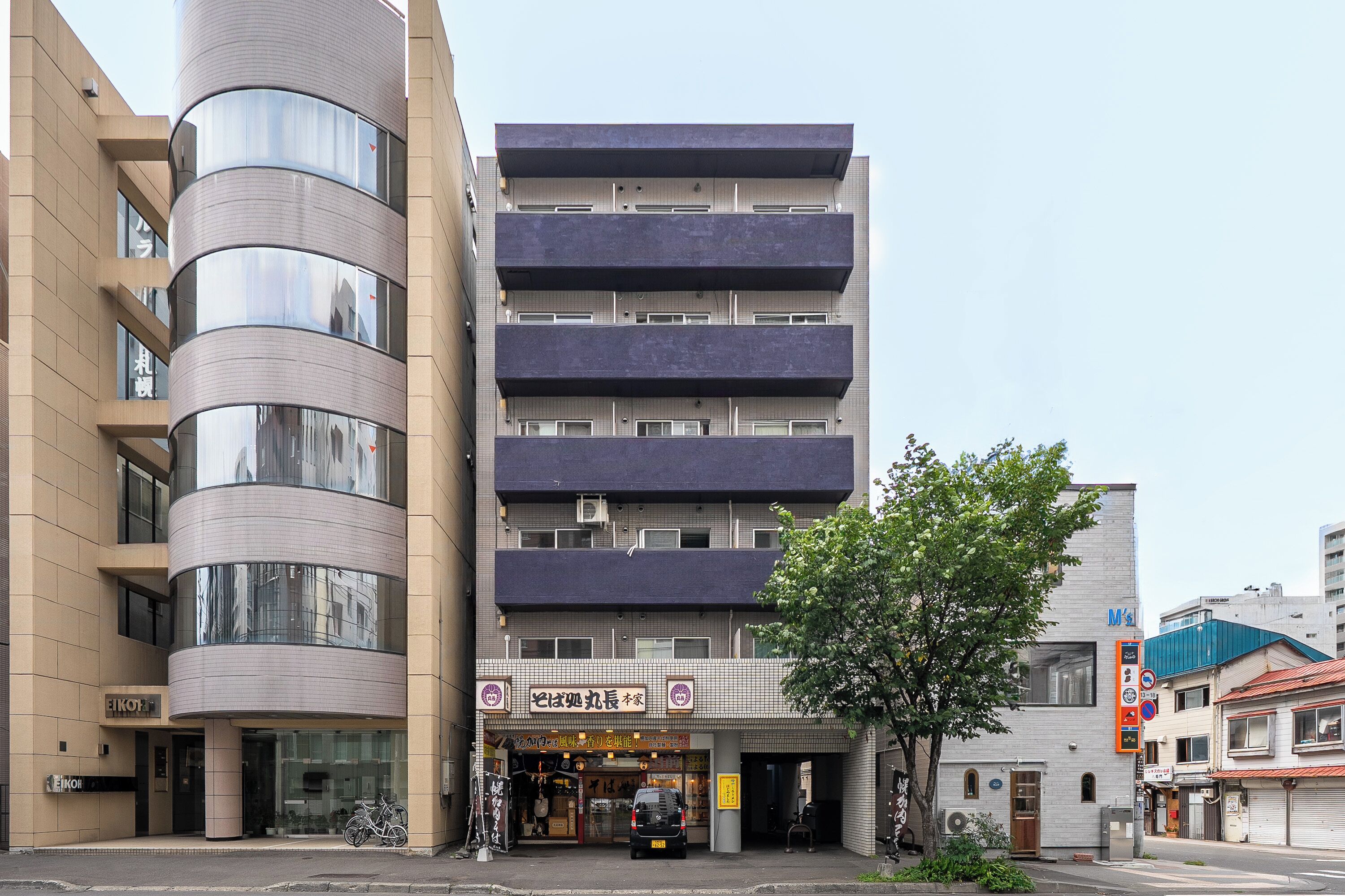 A multi-story building with a commercial ground floor featuring a restaurant and a parking area.