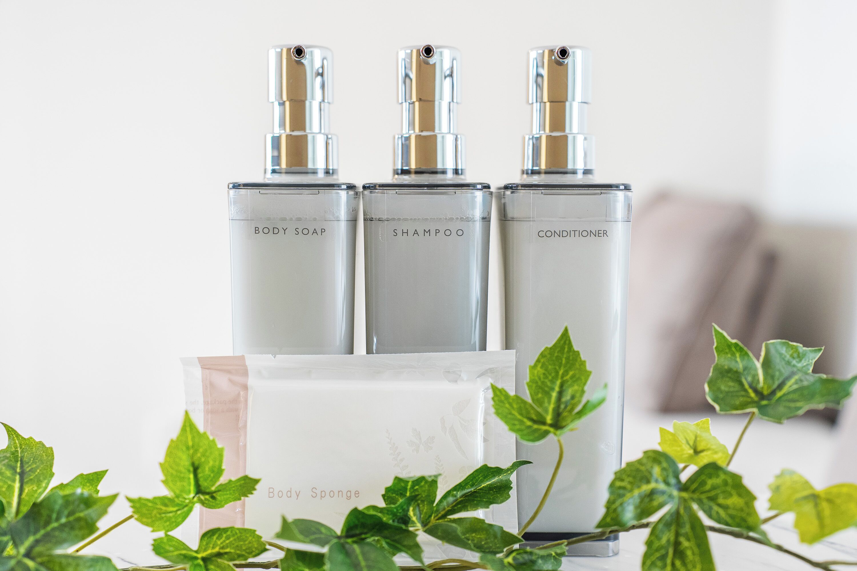 Three bottles labeled BODY SOAP, SHAMPOO, and CONDITIONER, with a BODY SOAP bottle in front.