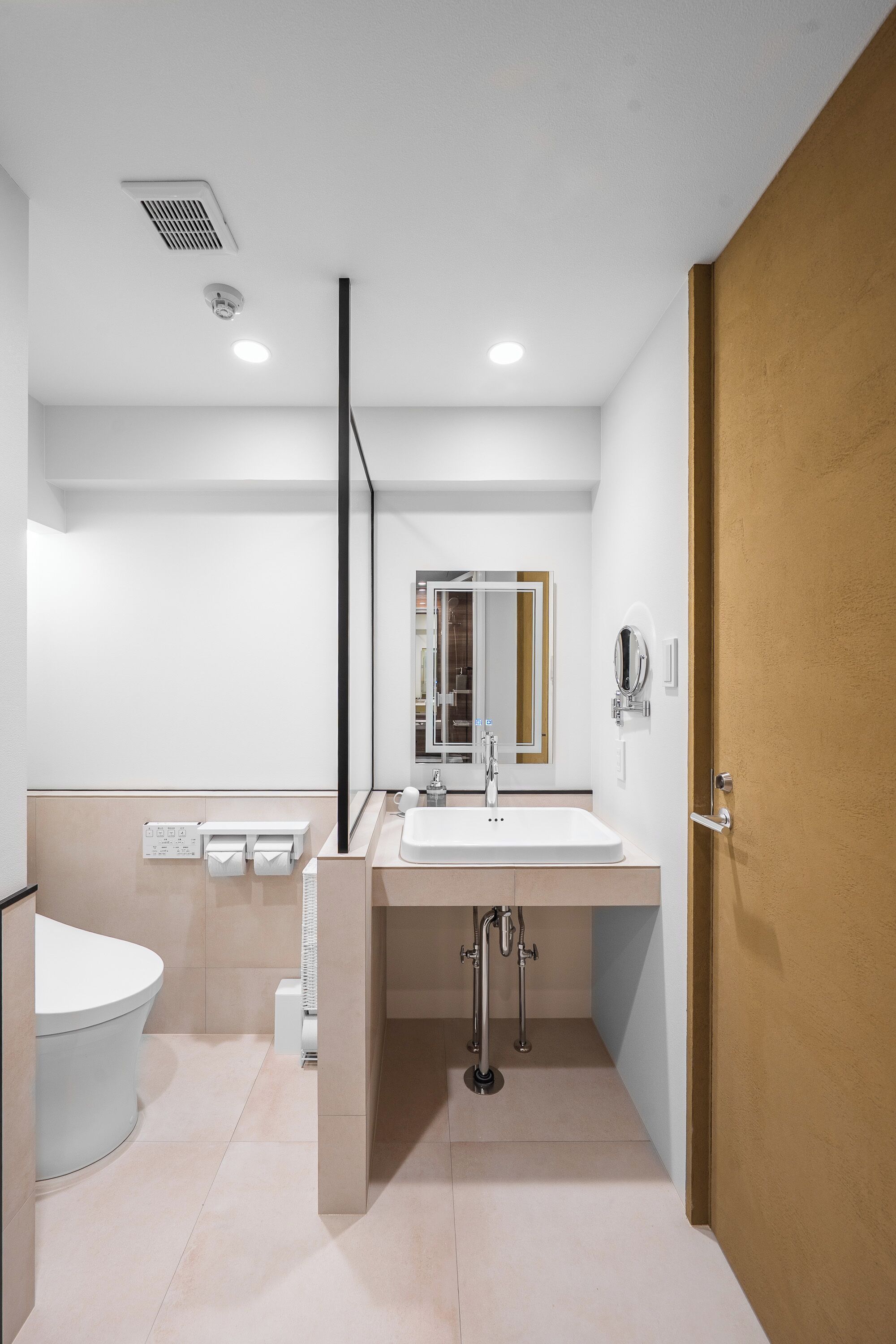 A modern bathroom with a white sink, mirror, and toilet.