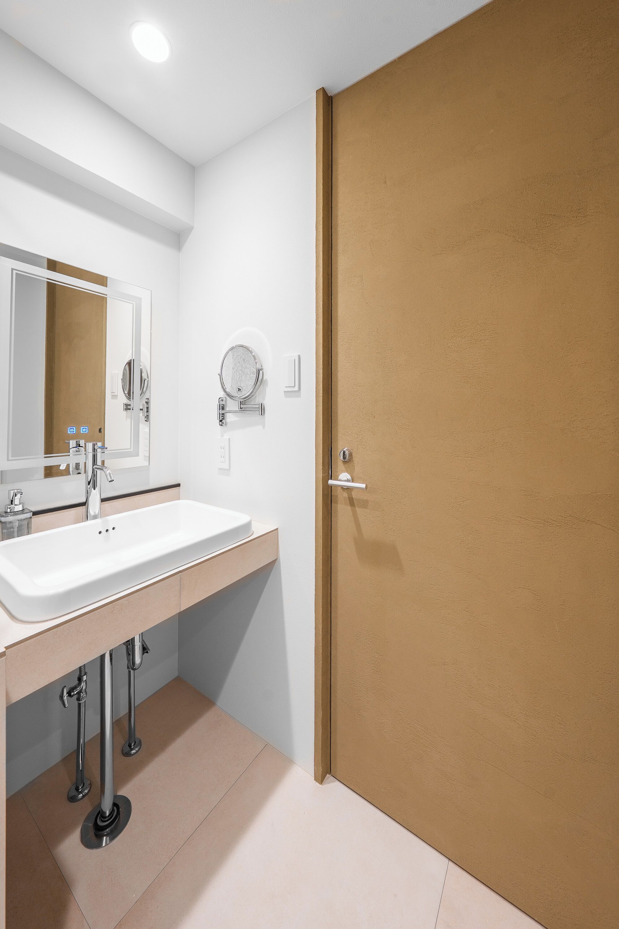 A bathroom with a white sink, mirror, and a wooden door.