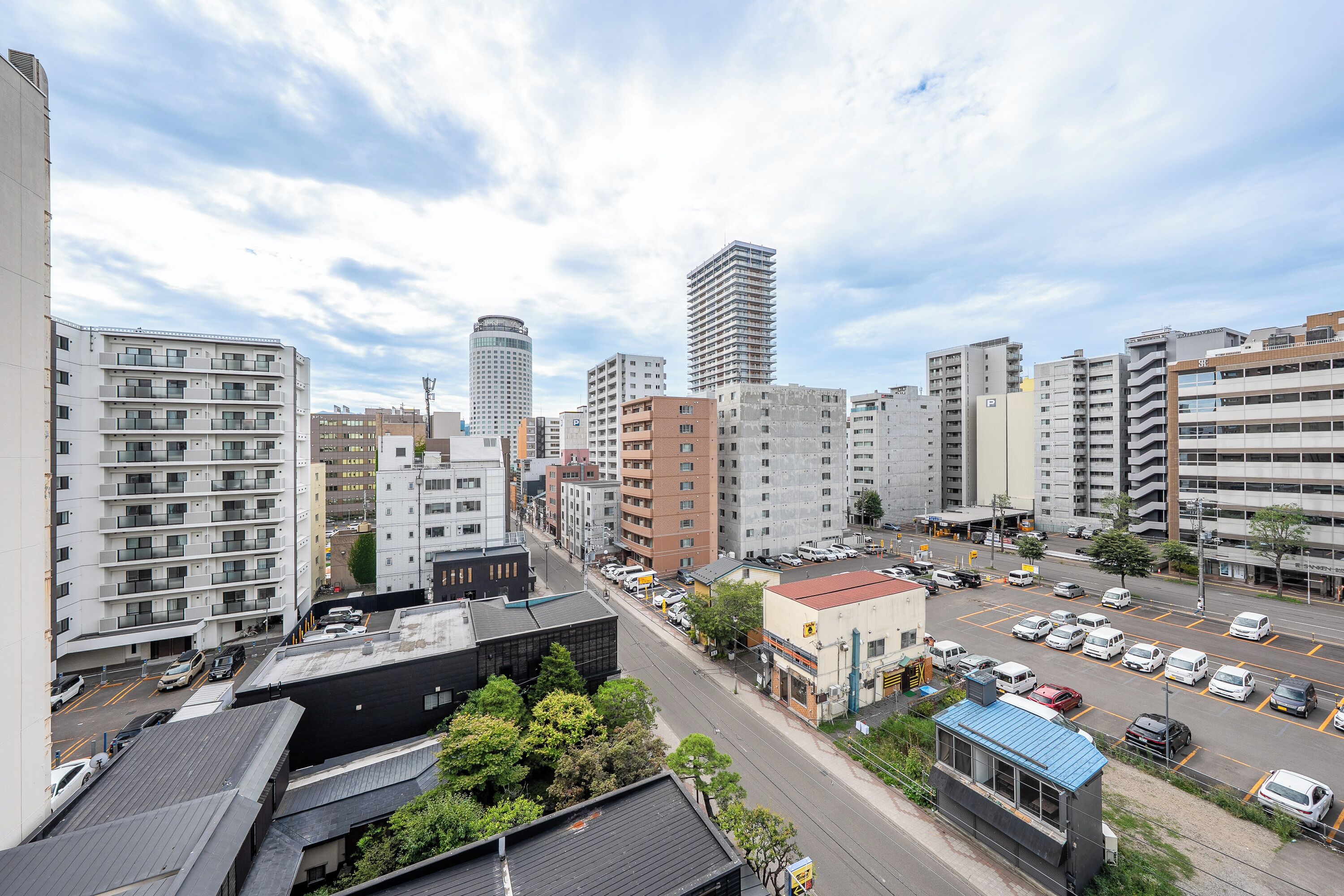 A cityscape with modern buildings, a parking lot, and a clear sky.