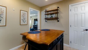 A dining area with a wooden table, blue placemats, and a wall-mounted wine rack. - The Dome Home<>3BR House 1mi to ND (South Bend)