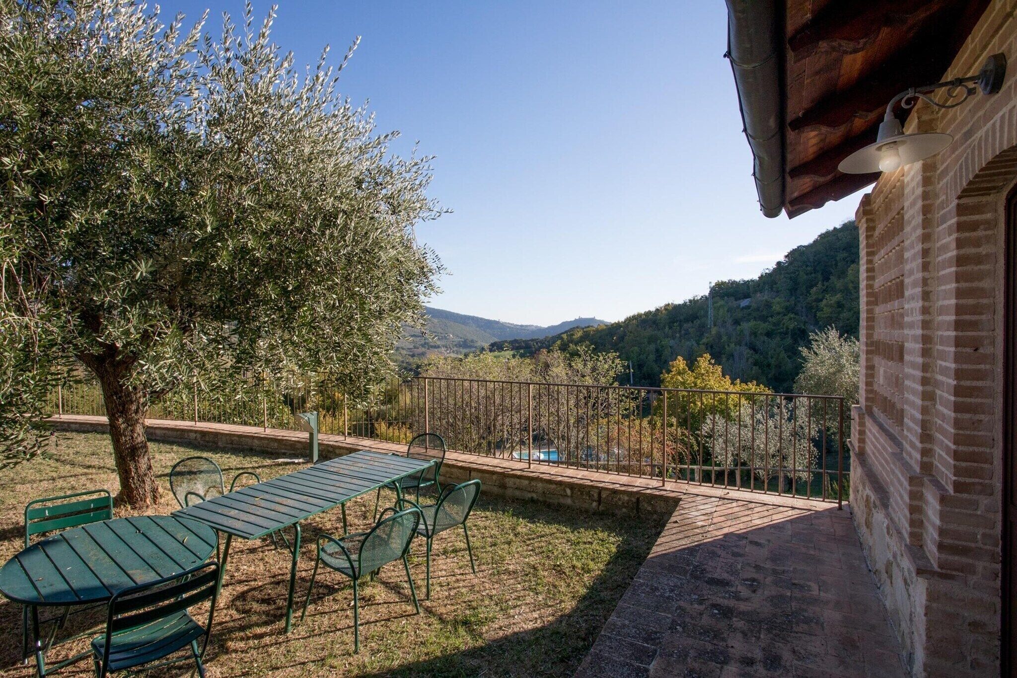 Une terrasse avec une table et des chaises, un arbre et une vue sur une vallée.