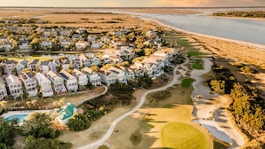 A coastal residential area with houses, a golf course, and a beach.