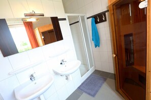 Une salle de bain avec deux lavabos, une douche et un espace de douche séparé par des parois en verre.